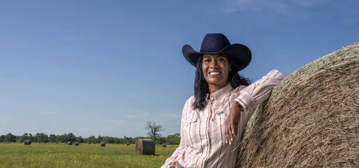 Kim Ratcliff leaning against a bale of hay
